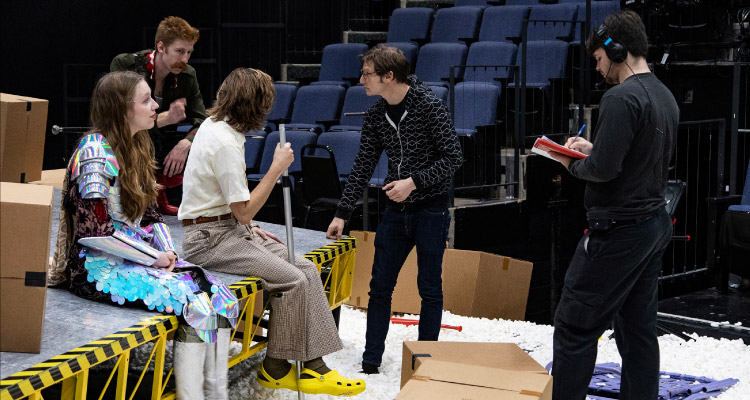 A graduate director gives notes to a cast of actors.